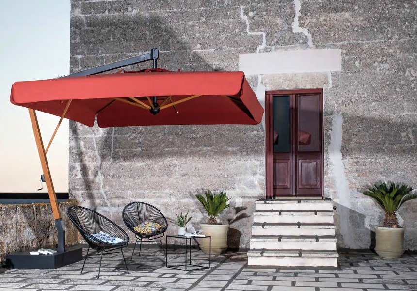 parasol przy starym budynku z czerwona czaszą po nim kilka krzeseł na ścianie drewniane drzwi i pięć schodków do nich prowadzace