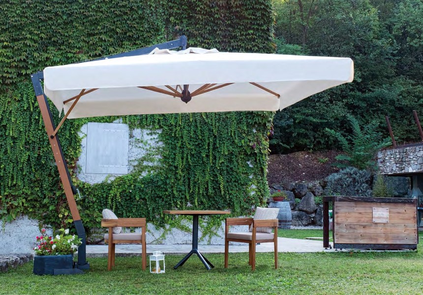 Parasol ogrodowy duży na tle zielonego ogrodu zze stolikiem kawowym i krzesłami